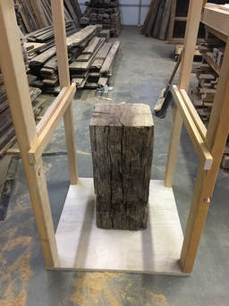 Picture of a reclaimed wood beam sitting the floor of the jig.
