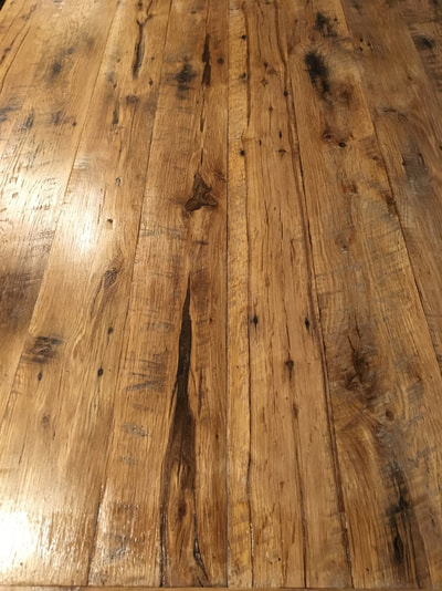 An up close picture of the table top. The picture shows some of the deep cracks in the wood along with nail holes and circular saw marks.