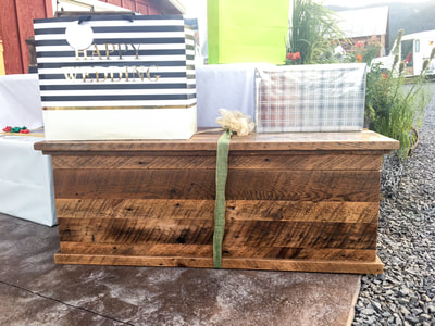 Front view of the reclaimed wood blanket chest. The blanket chest is wrapped with a ribbon and bow and has gifts on top of it.