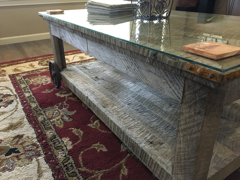 Angled view of the antique wheel and gray reclaimed wood coffee table. 