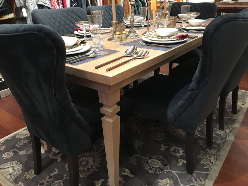 View showing the corner of the birch dining table with platewear and chars. 